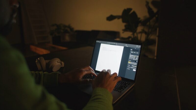 A person translating documents in a dimly lit room, with focus on the computer screen displaying text, symbolizing data security practices